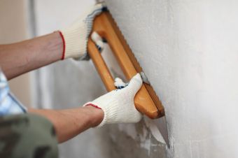 ПЕред окрашиванием стену выравнивают штукатурными составами